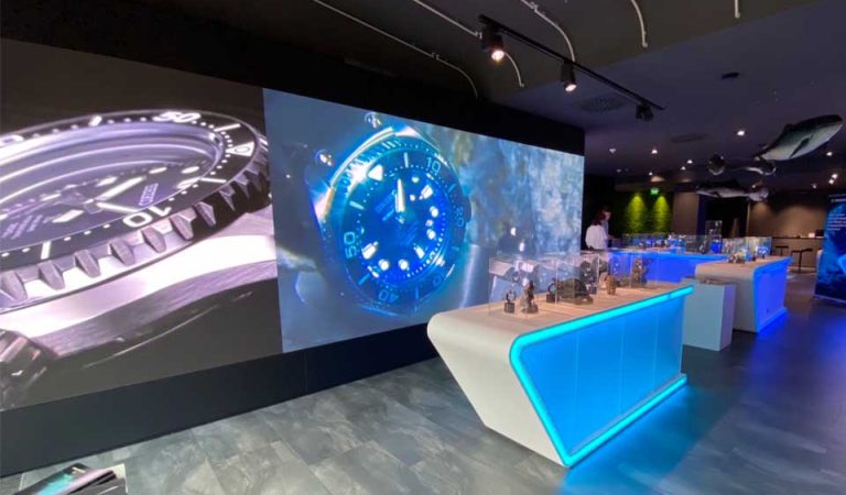 Seiko Taucheruhren, gezeigt auf einer LED Wand, mit Ozeaneum Ausstellungsobjekten davor